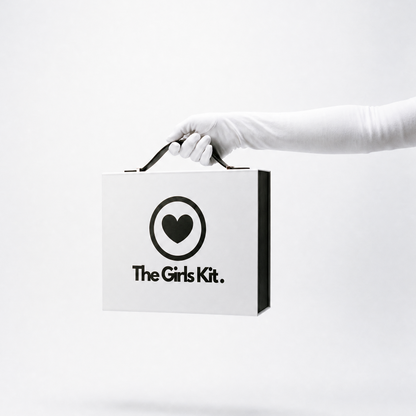 Hand holding a box labeled 'The Girls Kit' on a white background